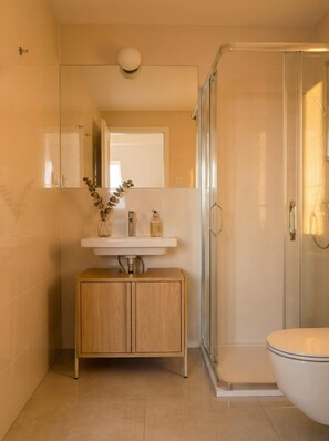 Ein modernes Badezimmer mit Duschkabine aus Glas, einem Holzwaschtisch und einem weißen Waschbecken.