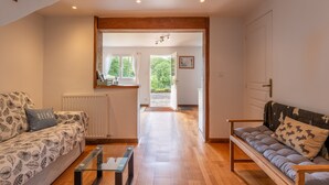 A spacious living area with a sofa, a coffee table, and a view through an open doorway to a kitchen and outside.