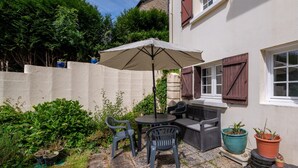 A patio with a table and chairs, a large umbrella, and potted plants.