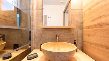 A modern bathroom with a large stone sink, a mirror above it, and a wooden vanity.