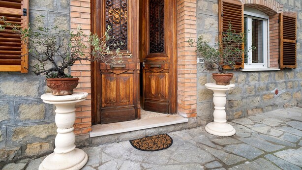 A stone building with wooden doors and shutters, a potted plant on a pedestal, and a small window with shutters. - Apartment 'Appartamento In Villa La Baronessa' with Private Garden and Wi-Fi (Sanremo)