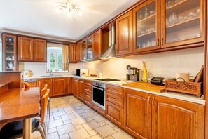 Une cuisine avec des meubles de rangement en bois, un évier, une cuisinière et une fenêtre.