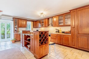Uma cozinha com armários de madeira, um espaço para vinhos e uma área de jantar com uma cadeira.