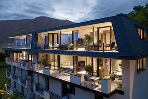 Un immeuble moderne à plusieurs étages, doté de grandes fenêtres, de balcons et offrant une vue sur les montagnes.