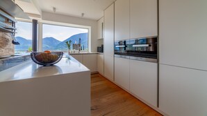 Eine moderne Küche mit einem großen Fenster, Holzboden und weißen Schränken.