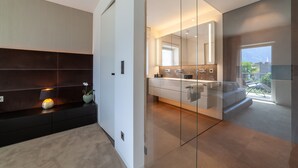 Ein modernes Badezimmer mit einer Duschkabine aus Glas, einem Waschtisch mit Spiegel und Blick ins Freie.