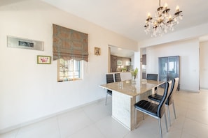 Una cocina moderna con comedor, una araña y una ventana con cortinas estampadas.