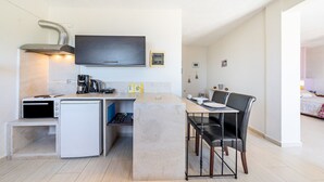 Eine kompakte Küche mit Einbauofen, Kaffeemaschine und kleinem Kühlschrank.