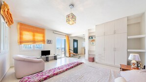 Ein modernes Schlafzimmer mit Bett, Sitzecke, Fernseher und Kleiderschrank.