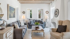 Un salón con sofá, sillón, mesa de centro y adornos decorativos.