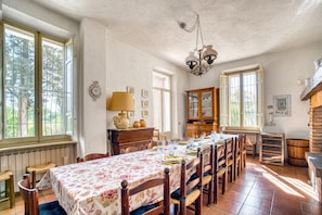 Une salle à manger avec une longue table, des chaises, un lustre et un buffet.