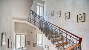 Un interior con varios niveles, una escalera, cuadros en las paredes y ventanas.