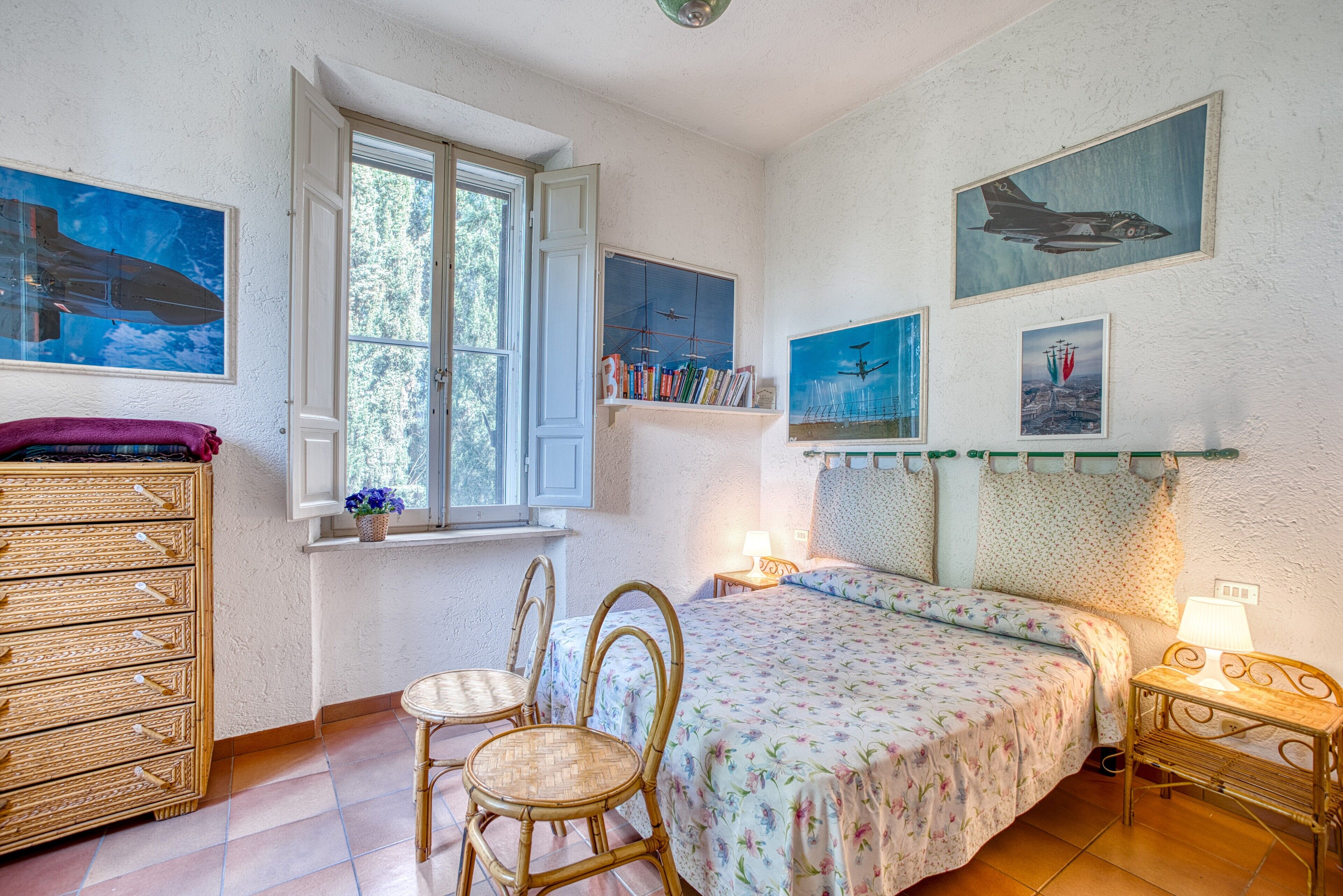 Ein Schlafzimmer mit einem Bett, zwei Stühlen, einer Kommode und einem Fenster.