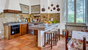 Una cocina con una isla central, taburetes de madera, una mesa de comedor y un ventanal con vistas.