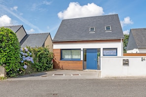 A modern two-story house with a blue door, a small window, and a grey roof. - Maison récente à 300 m de la mer*** (Carantec)