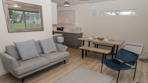 Un salon moderne avec un canapé gris, un fauteuil bleu et une table à manger en bois.