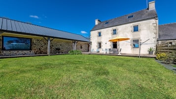 Un bâtiment en pierre doté d’une grande fenêtre et d’un patio couvert.