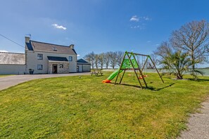 A grassy area with a swing set and a building with a stone facade.