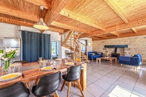 A dining area with a wooden table set for four, black chairs, and a staircase leading to an upper level.