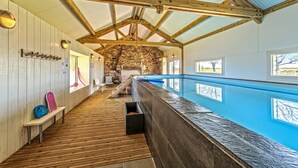 A wooden interior with a pool, benches, and a stone wall. - Holiday Home with Private Heated Pool, Private Terrace, Garden and Wi-Fi (Plouguerneau)