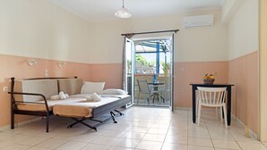A room with a bed, a table with chairs, and a sliding glass door leading to an outdoor area.