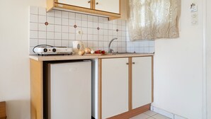 Een kleine keuken met een inbouwkoelkast, een kookplaat en een spoelbak.