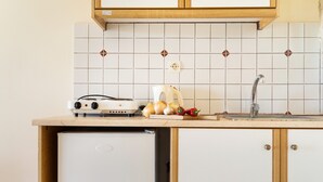 Een keuken met een ingebouwde oven, een spoelbak en een kleine koelkast.