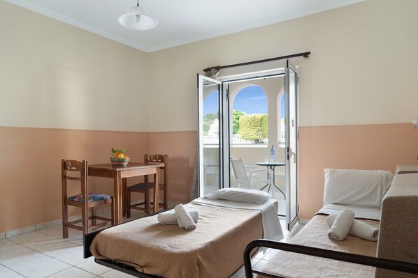 Habitación de hotel con cama, escritorio, silla y balcón con vistas.