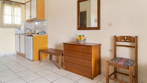 Una cucina compatta con una panca, un mobiletto in legno con cassetti, una sedia e uno specchio a parete.