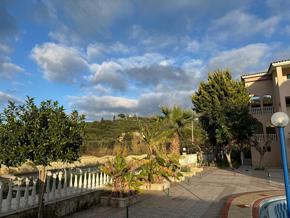 A paved pathway, a white balustrade, and a building with a balcony.
