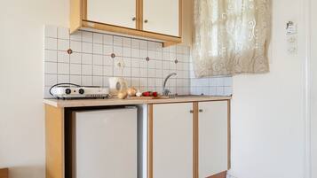 Een kleine keuken met een inbouwkoelkast, een kookplaat en een spoelbak.