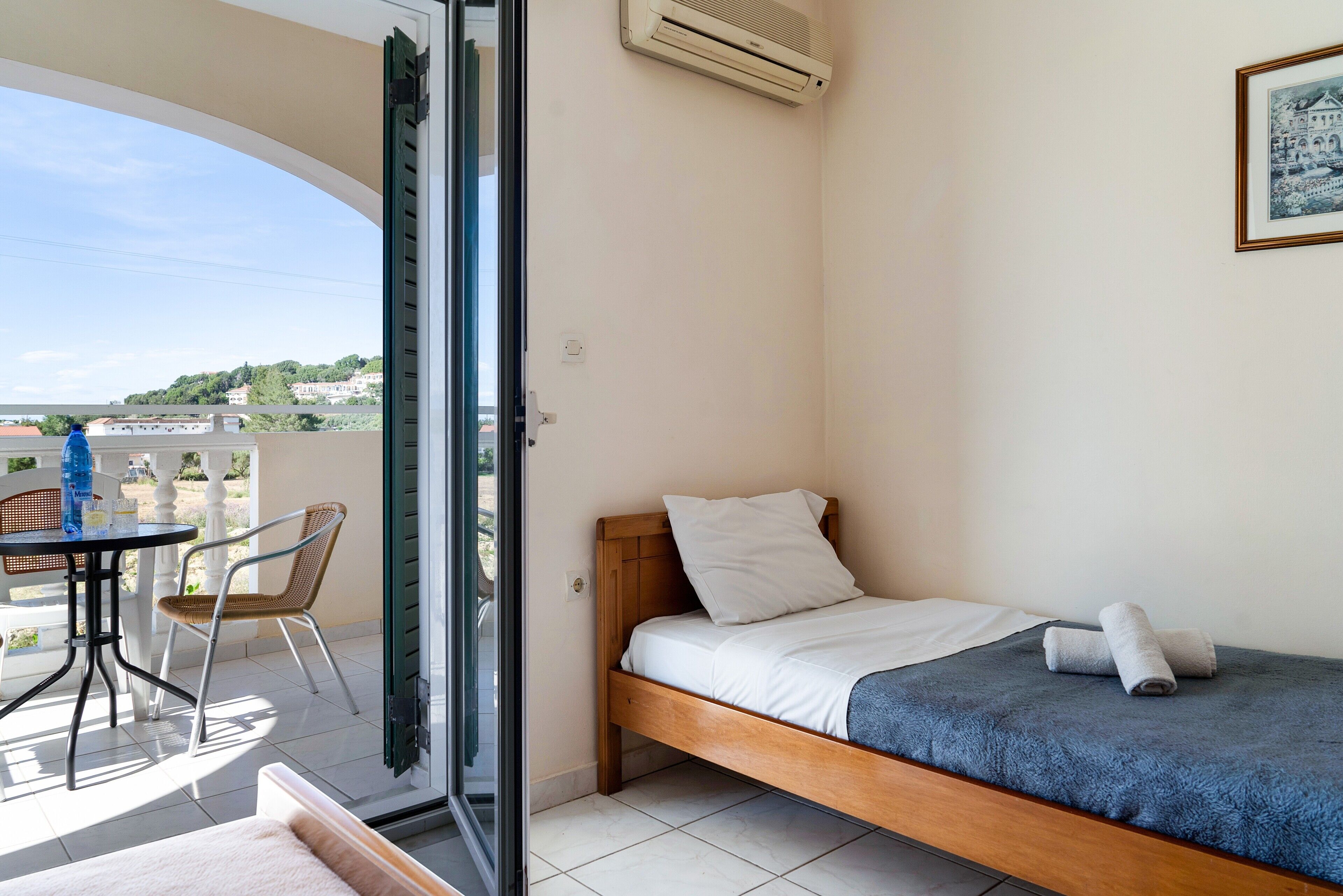 A room with a bed, a table with chairs, and a view of the outside.