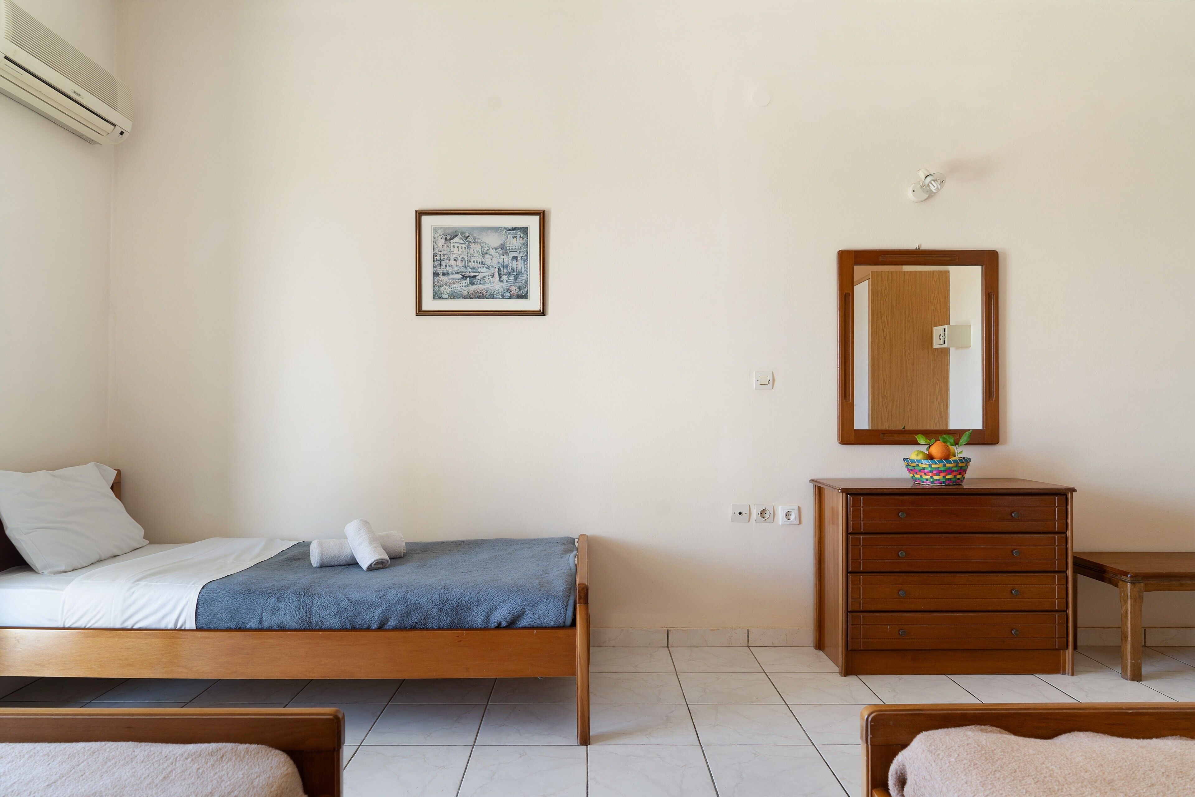 A bedroom with a bed, a dresser, a mirror, and a framed picture on the wall.