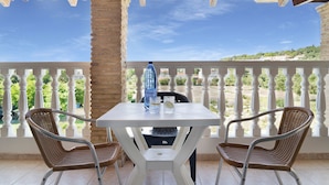 A covered outdoor area with a table and two wicker chairs, a bottle, and glasses on the table. - Studio 'Sandy Maria Studio 402' with Shared Pool, Wi-Fi (Zante)