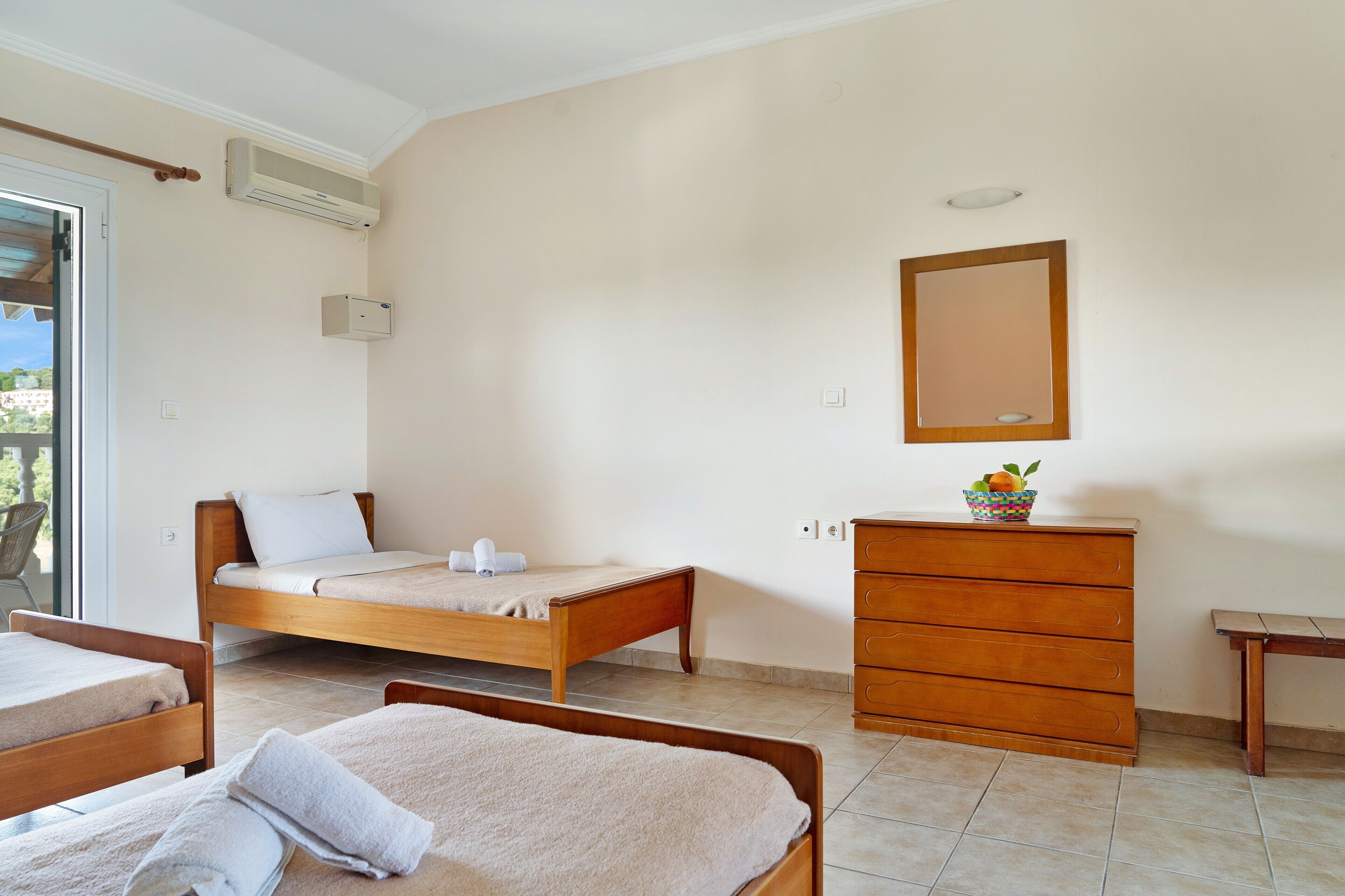 A bedroom with two beds, a dresser, a mirror, and an air conditioning unit.