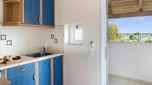 Une cuisine avec des meubles de rangement bleus, un évier et une fenêtre donnant sur un quartier résidentiel.