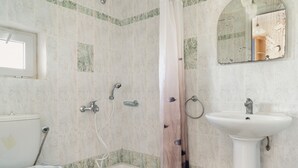 Une salle de bain équipée d’une douche, de toilettes, d’un lavabo et d’un miroir.