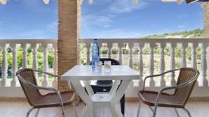Un espace extérieur abrité, avec une table et deux chaises en osier, une bouteille et des verres posés sur la table.