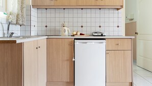 A kitchen with wooden cabinets, a white dishwasher, and a tiled backsplash. - Studio 'Sandy Maria Studio 504' with Shared Pool, Wi-Fi  (Zante)