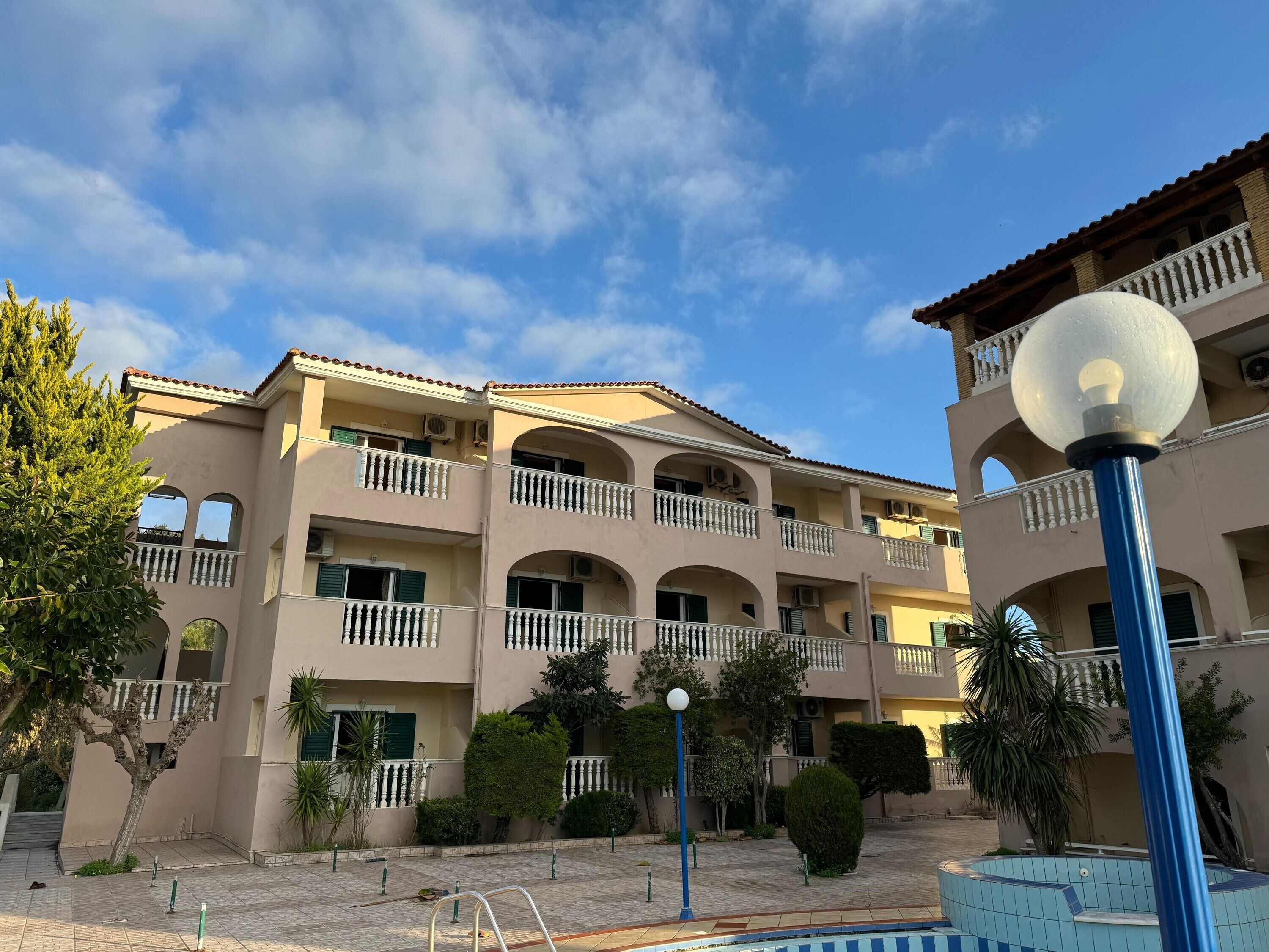 A multi-story building with balconies, a swimming pool, and a clear sky.