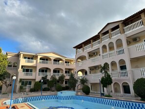 Un hotel con varios balcones, piscina y un patio con árboles.