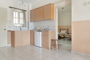 Uma cozinha com armários de madeira, lava-louças e janela com cortinas.