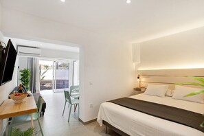 A modern hotel room with a bed, bedside table, and a dining area with chairs and a table. - Vacation Home '4ever2 (copy)' with Wi-Fi and Air Conditioning (Corralejo)