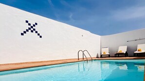 A swimming pool with a white wall and a blue sky.