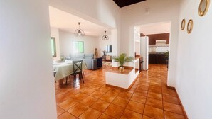 A spacious living area with a dining table, sofa, and kitchen in the background.