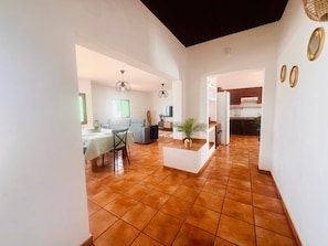 A spacious living area with a dining table, sofa, and kitchen in the background.
