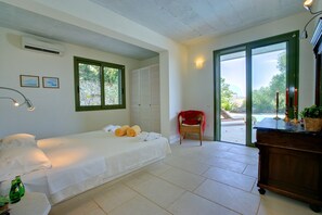 A bedroom with a bed, a chair, a desk, and a view of the outdoors.
