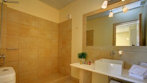 Un baño con ducha, inodoro, lavamanos y espejo.