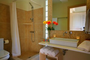 A bathroom with a shower, toilet, sink, and a mirror.