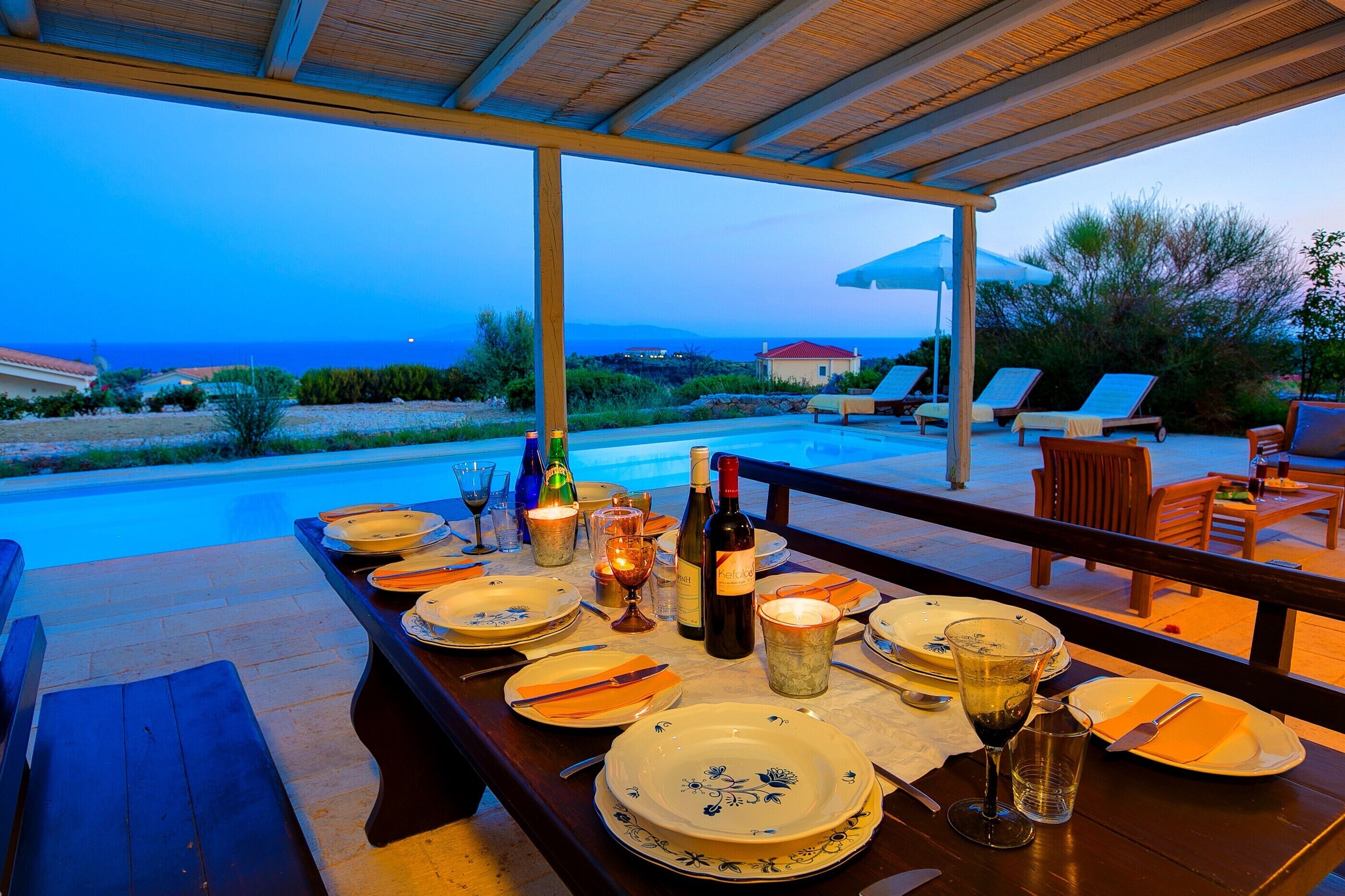 Une table à manger dressée pour deux personnes, avec vue sur la mer et les montagnes.